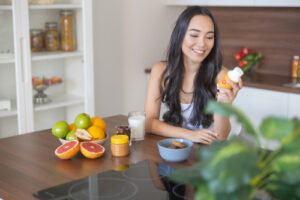 Smiling girl with a bottle of vitamins sitting at the kitchen table
