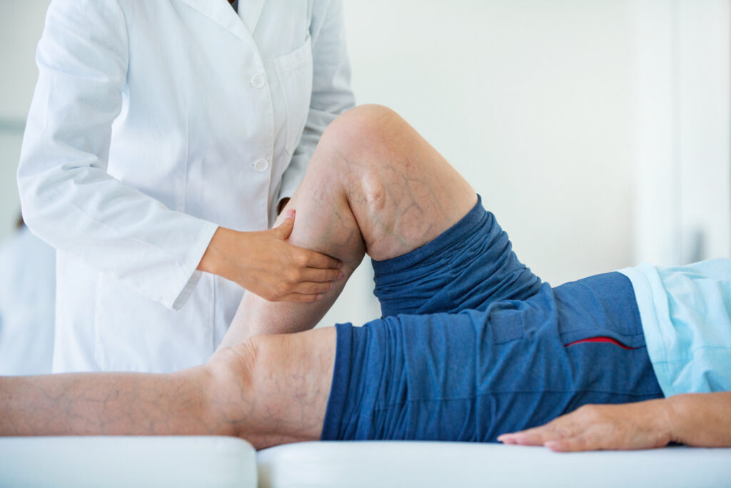 Senior woman in a massage treatment. Doctor examining a man's legs before PAD care on Long Island
